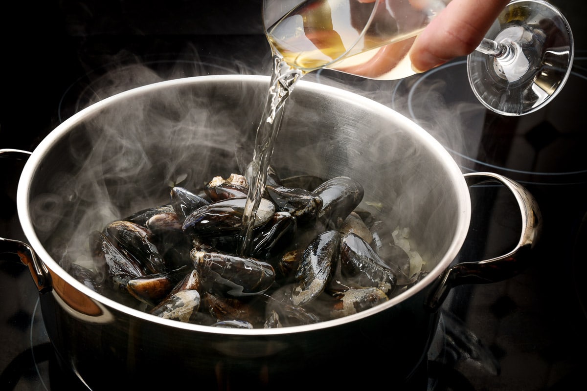 Steaming mussels in a pot being deglazed with white wine