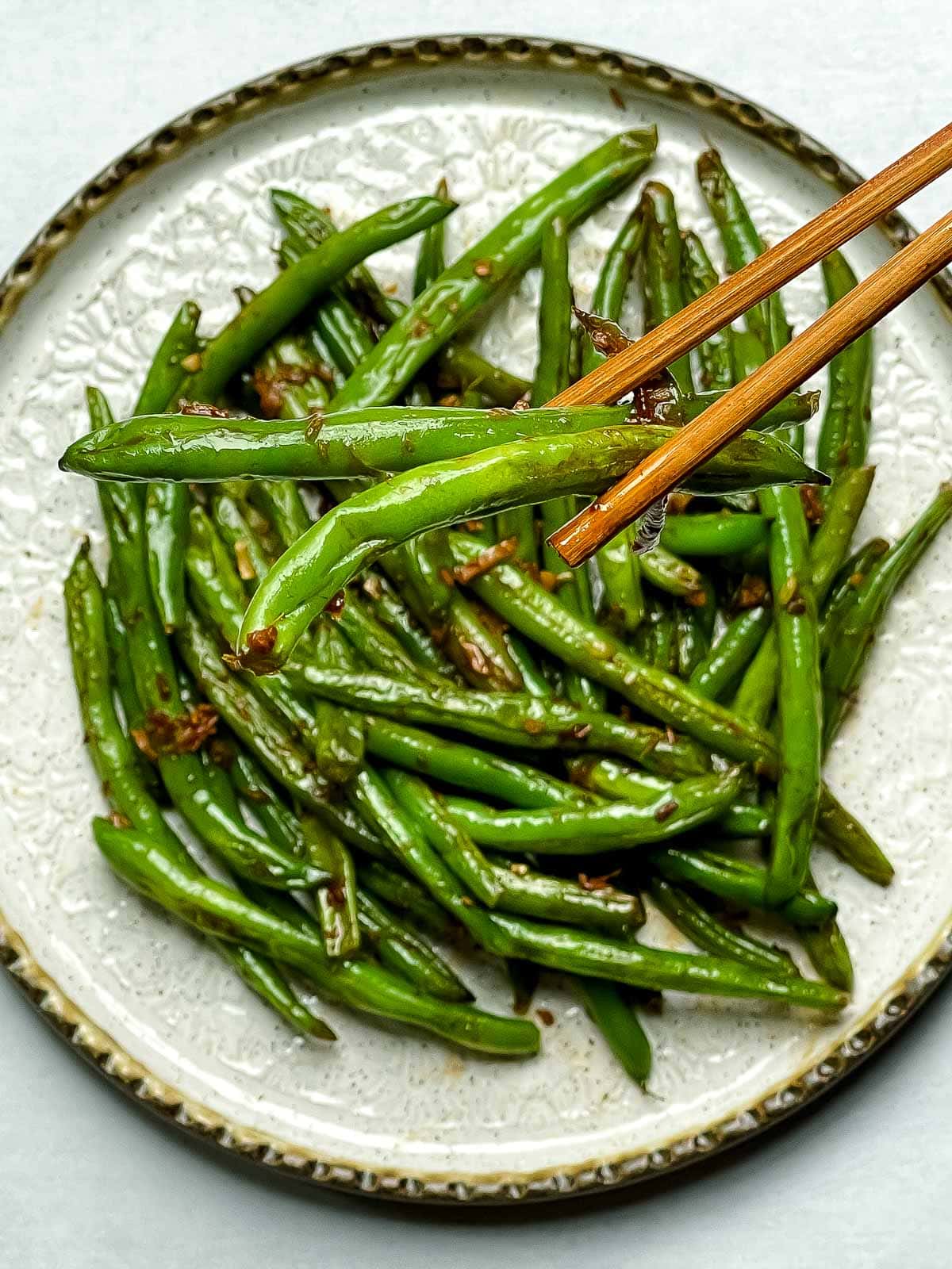 Chinese Garlic Green Beans and chopsticks on a round white bowl.