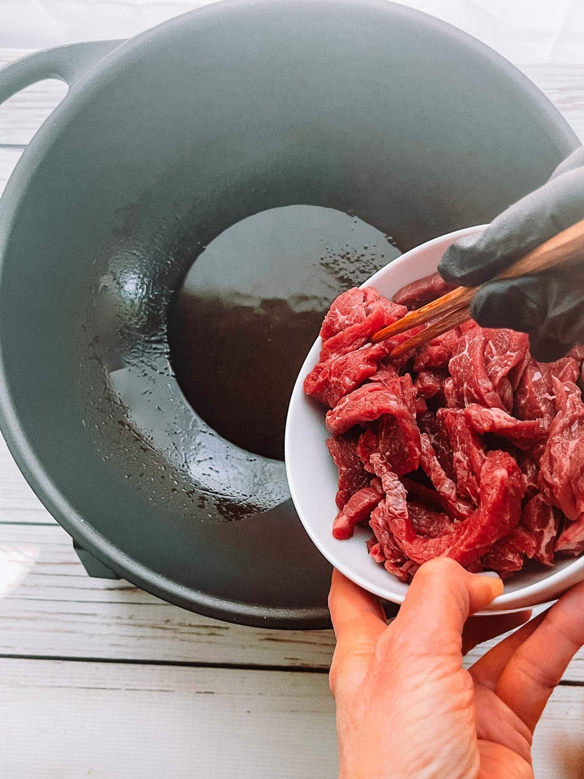Adding flank steak strips to a hot wok.