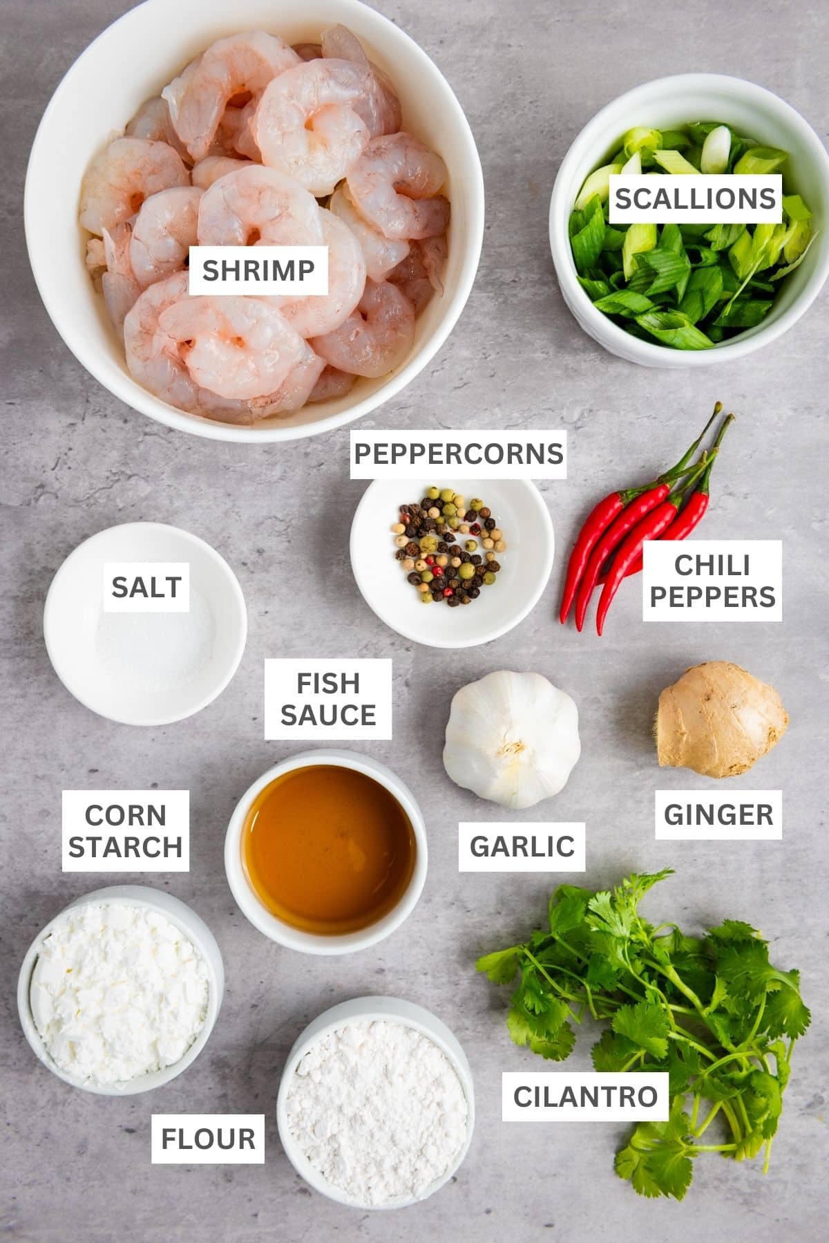 Labeled ingredients in small bowls for making Chinese salt and pepper shrimp on top of a gray surface.