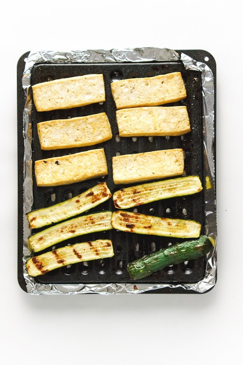 Grilled slices of tofu and zucchini on an oven grill tray.