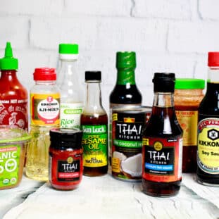 A compilation of Asian pantry products on top of a white wooden board.