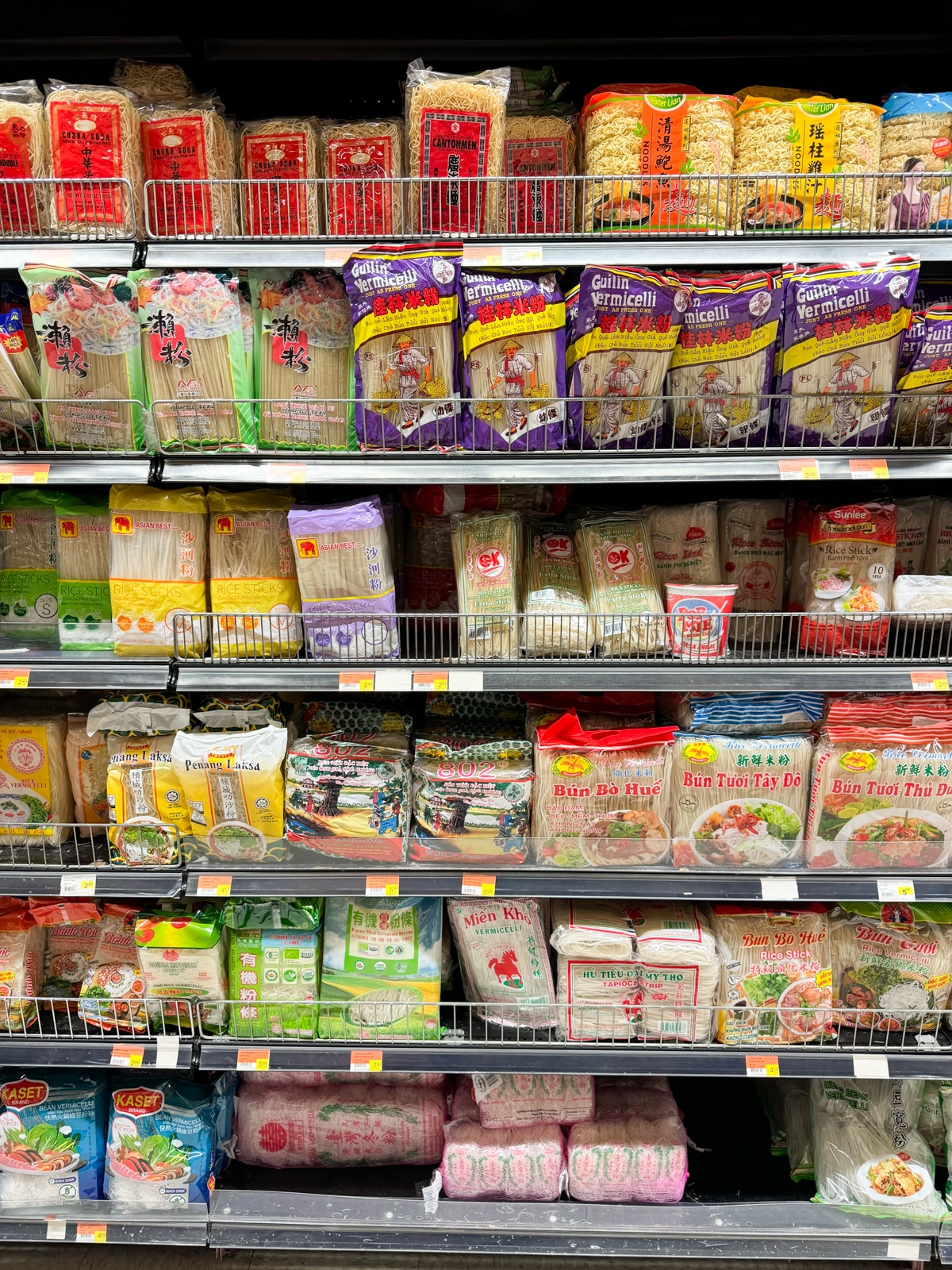 Stacked shelves filled with packages of rice noodles in various sizes.