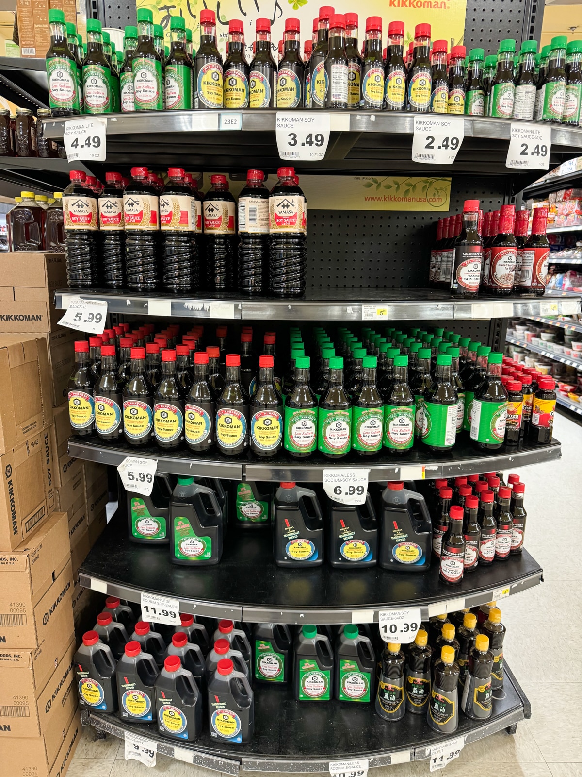 Tiered shelves at an Asian market with a large selection of soy sauces.