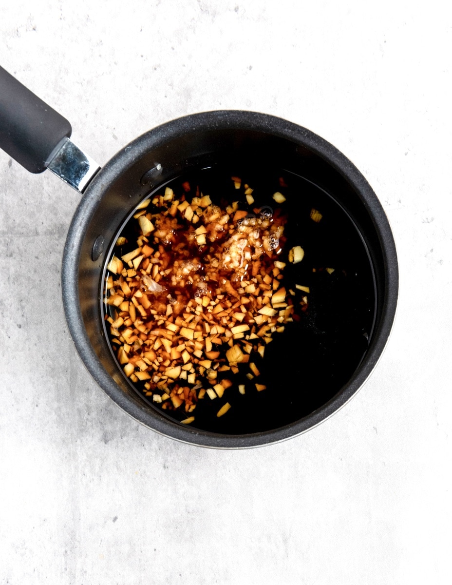 Teriyaki sauce in small sauce pan on top of a gray and white surface.