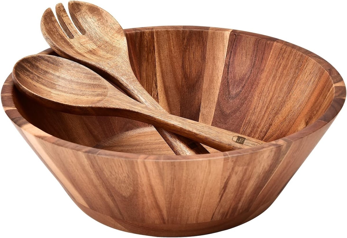 Wooden salad bowl with set made out of acacia wood on a white background.